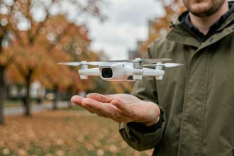 Homme tenant un mini-drone Parrot dans la main avant un vol de prise de vue en extérieur dans un parc urbain