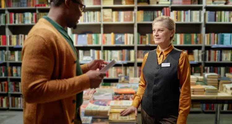 Middle Aged Caucasian Woman Assisting Young Black Man in Bookstore