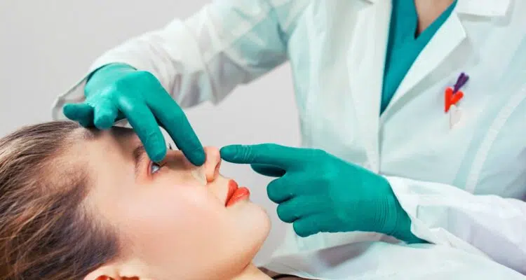 Rhinoplasty, the surgeon hands touches the patient s nose. People, cosmetology, plastic surgery and