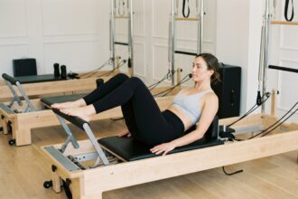 Femme pratiquant le Pilates Reformer dans un studio épuré au quartier Monceau, allongée sur le chariot avec une posture précise et sereine