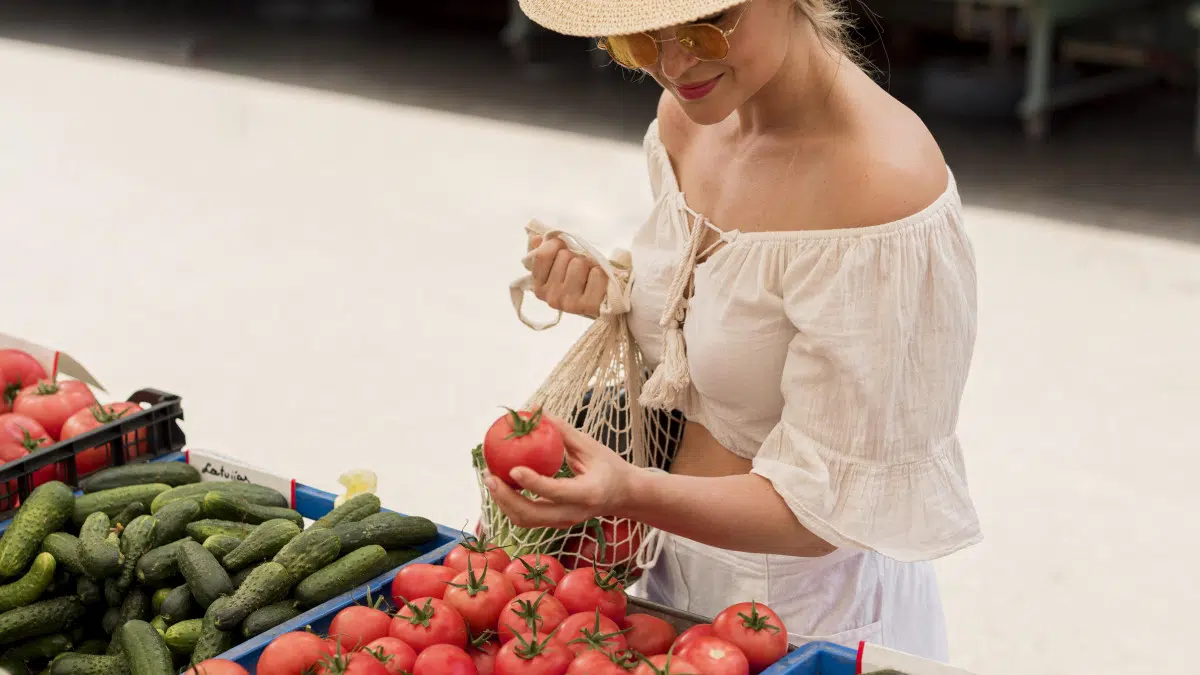 Une femme fait son marché et choisi des tomates